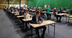 kilkudziesięciu uczniów siedzi przy stolikach na hali Milenium