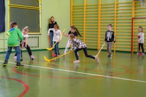 dzieci grają w hokejna na sali gimnastycznej