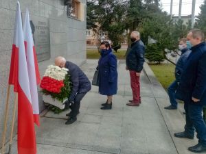 burmistrz Piotr Irla składa biało-czerwone kwiaty pod tablicą pamiątkową, stoją Danuta Dębska Przewodnicząca Rady Miasta,...