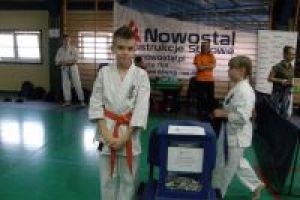 Przeszklona urna z zebranymi środkami wraz z uczestnikiem turnieju karate