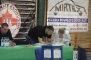 Widok na przeszkloną urnę, w tle sędziowe turnieju karate