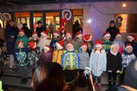 kilkanaścioro dzieci przed MDK w czapkach św. Mikołaja, za...