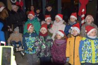 kilkanaścioro dzieci przed MDK w czapkach św. Mikołaja, za...
