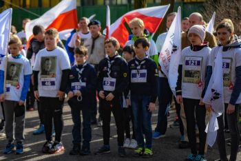 uczestnicy biegu w koszulkach z wizerunkami żołnierzy wyklętych, w tle flagi Polski