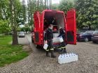 strażacy OSP wyjmują ze strażackiego samochodu płyny do dezynfekcji