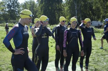 grupa pływaczek w żółtych czepkach przygotowuje się do startu