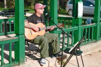 Robert Skrzypek z gitarą i przy mikrofonie pod altaną parkową