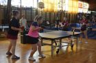 gra deblowa dziewcząt przy stole tenisowym, na drugim planie sędzia