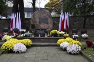 pomnik ofiar II wojny światowej i pomnik AK, chryzantemy i flagi Polski