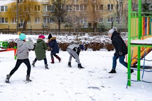 dzieci rzucają się śnieżkami na placu zabaw