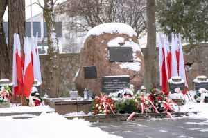 pomnik ofiar II wojny światowej i pomnik AK na cmentarzu wojskowym, biało-czerwone flagi i wiązanki