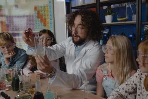 nauczyciel i czworo uczniów wykonuja doświadczenie z chemii