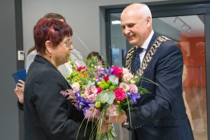 burmistrz wręcza bukiet kolorowych kwiatów jubilatce