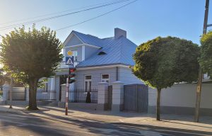 budynek parterowy, w kolorze szarym, przed nim drzewa