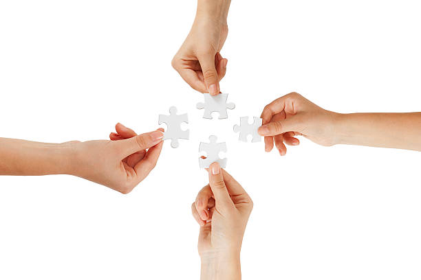 zdjęcie łączenia puzzli przez cztery osoby